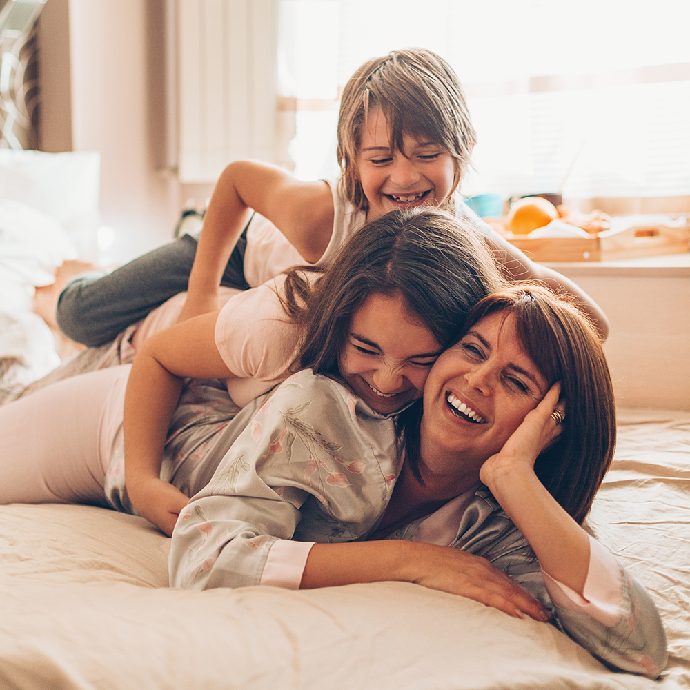 Mère et ses enfants qui rient dans un lit